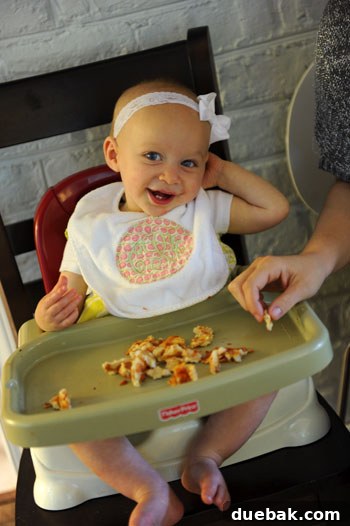 Clara, the birthday girl, taking a break from eating pizza to smile at the camera.
