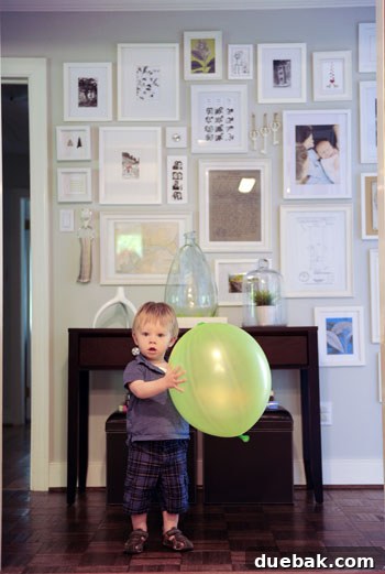 Clara's cousin John with a giant balloon, looking at a hallway frame wall.