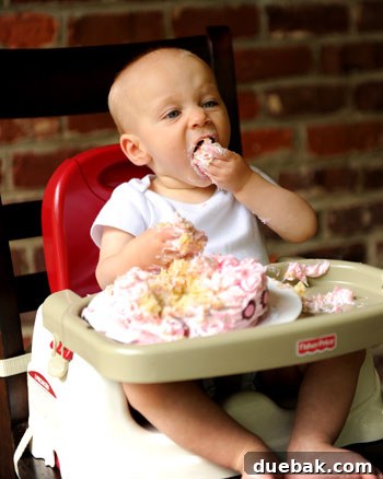 Clara enthusiastically digging into her smash cake, making a joyful mess.