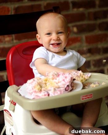 A close-up of Clara's joyful, frosting-covered face during her smash cake.