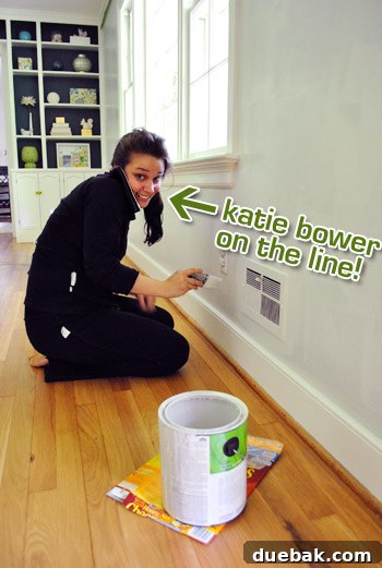 Moonshine by Benjamin Moore: The Serene Light Gray You've Been Searching For 9 Humorous photo of a person wearing an inside-out black sweatsuit, used as painting clothes, holding a paint roller during a home DIY project.