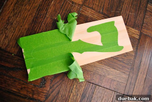 Removing painter's tape to reveal the wood grain of the number seven