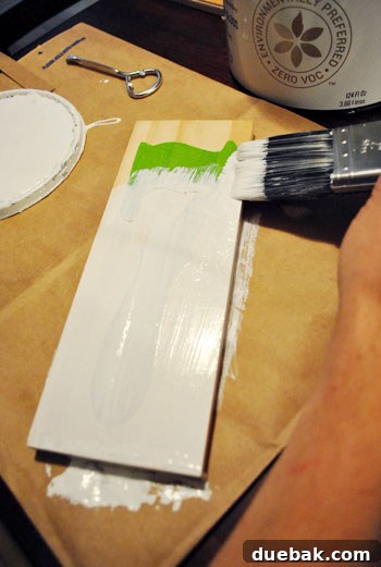 Applying the first coat of white paint to the stenciled wood plaque