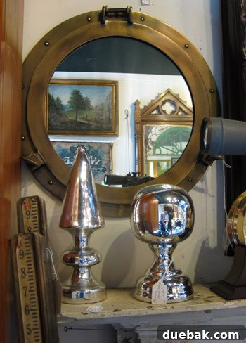Inside the Antique Mall, featuring oversized mercury glass finials and an antique bronze porthole mirror, showcasing unique vintage decor.