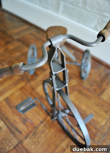 Another view of the metal tricycle, showcasing its rustic patina and potential as a unique decorative piece in a home office.