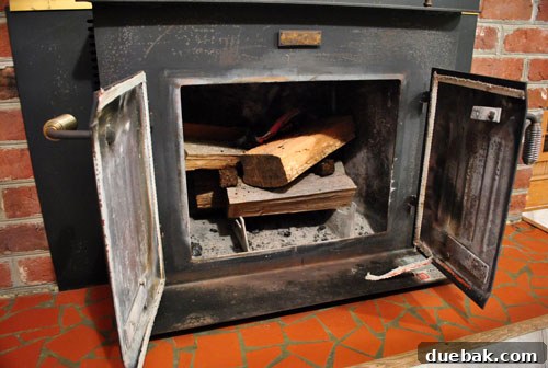 A person pulling at the metal flashing of the wood stove