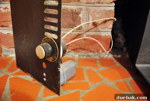 Wires connected to a fan at the back of the wood stove