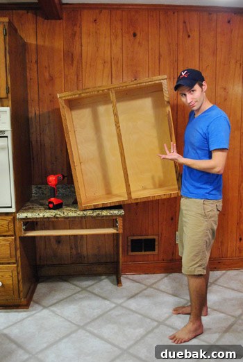 Removing Cabinets and Repairing Vinyl Flooring 13 Person posing with the removed upper cabinet, making a Vanna White-like gesture