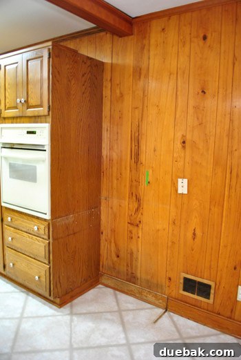 Removing Cabinets and Repairing Vinyl Flooring 18 Close-up of the wall and cabinet after desk removal, showing glue residue and missing trim