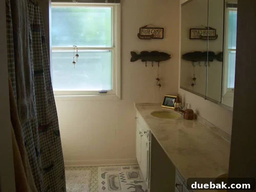 dingy-and-dated-bathroom-before Dated guest bathroom with yellow floor tiles, yellow sinks, and a fishing themed plaid curtain, looking dim and old-fashioned before the renovation.