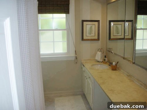 inexpensively-updated-bathroom-after-picture Updated guest bathroom with new white sinks, light colored peel and stick floor tiles, and a soft white waffle weave shower curtain, creating a bright, spa-like neutral environment.
