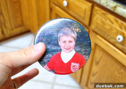 Vintage soccer button with a photo of a young boy John, showing a resemblance to Clara, next to cabinet knobs.