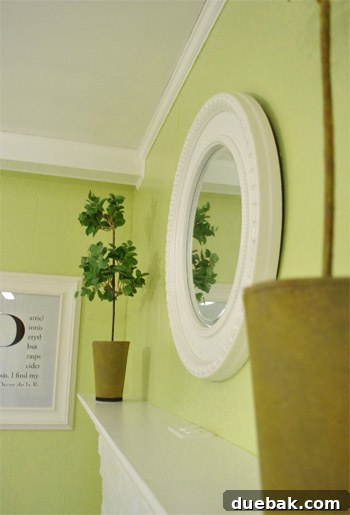Revamping Our Wood Paneling with Paint 17 Decorated fireplace with white frames, round mirror, and green walls
