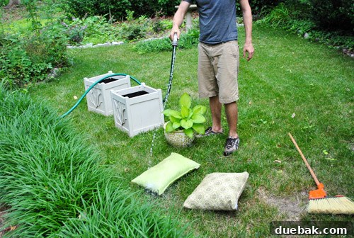 Cleaning old outdoor planters and pillows with a hose