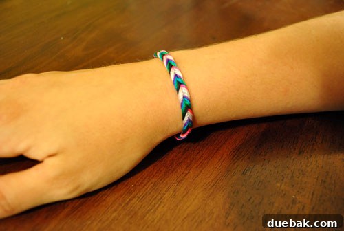 Two hands wearing friendship bracelets