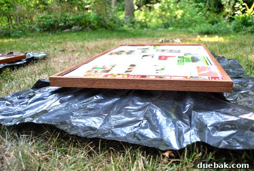 From Drab to Fab: Spray Paint Frame Makeover 12 Spray painting setup with frames propped on rocks, covered with newspaper