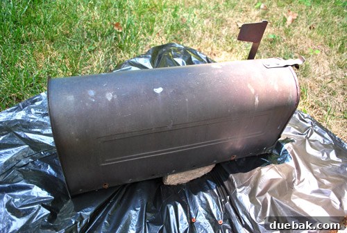 Close-up of old, worn mailbox, showing faded paint and minor damage