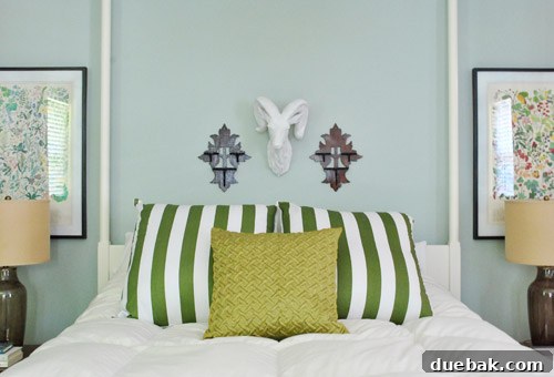 Frame Fusion: Spray Paint for Cohesive Style 2 Boldly striped euro pillows on a bed, paired with botanical art prints