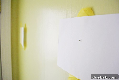 From Drab to Dreamy: Our Laundry Room Makeover 7 Paper template taped to wall, marking exact screw positions for mirror installation