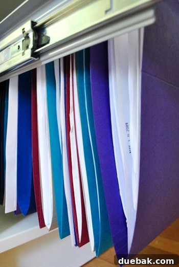 Clever Printer Concealment Ideas 15 Close-up detail of the colorful hanging files arranged inside a file cabinet drawer, showcasing their vibrant hues.