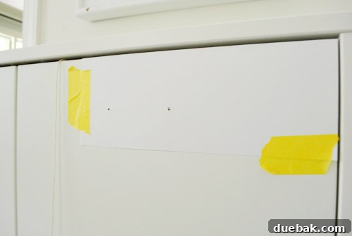 Clever Printer Concealment Ideas 5 Card stock template flipped over and aligned on the second cabinet door, ready for symmetrical hole drilling.