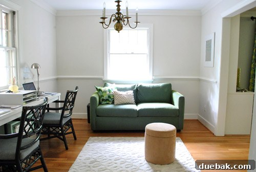 View of the home office from the kitchen, featuring a green sleeper sofa under a window.