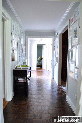 Wide, light-filled hallway in the current house, adorned with a large family photo gallery