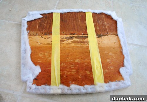 First layer of extra-loft batting applied to the taped wooden seat