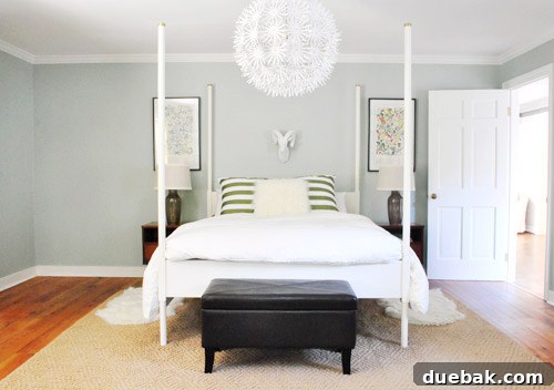A bedroom shot showing pillows arranged horizontally on a bed, alongside mid-century nightstands and decorative elements.
