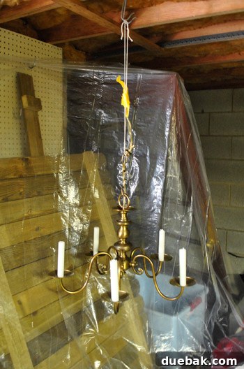 Revitalize Your Old Chandelier With Paint and a Shade Swap 19 Sherry preparing to spray paint the chandelier in the basement