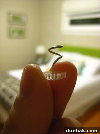Close-up of a bed skirt pin twisted into a box spring, holding the bed skirt perfectly in place.