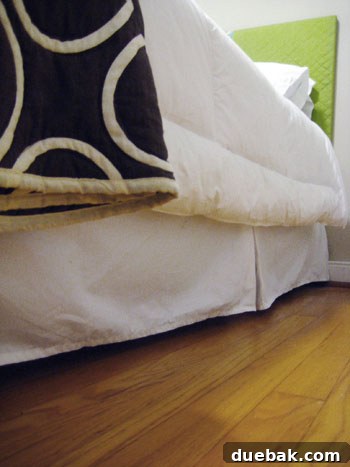 A perfectly taut bed skirt, held in place by discreet pins, displaying a clean and elegant bedroom aesthetic.