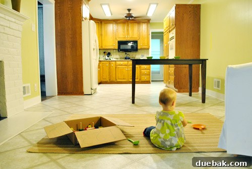 Child playing on a rug near the kitchen peninsula, demonstrating ease of supervision
