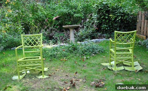 Mastering Chair Painting 11 Both grellow-painted chairs sitting in a yard, drying after the spray painting process, looking vibrant and ready for upholstery.