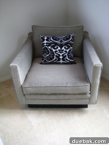 Reupholstered chair showcasing a modern black and white checkered fabric, complemented by a vibrant decorative pillow.