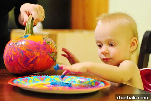 Toddler Clara painting a pumpkin with her hands