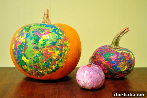 Hand carefully peeling painter's tape off a wet painted pumpkin