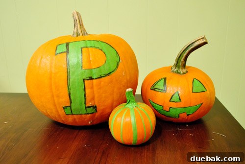 Three pumpkins with tape stencils completed, lined up and ready for painting