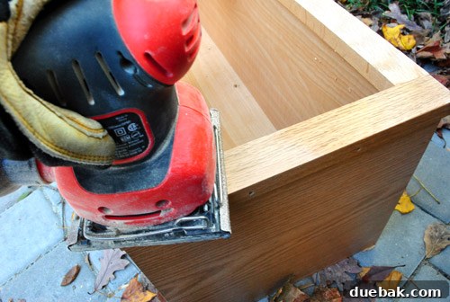 DIY Built-In Refrigerator Installation 6 Plywood piece being sanded smooth, with Kreg jig holes visible, preparing for paint
