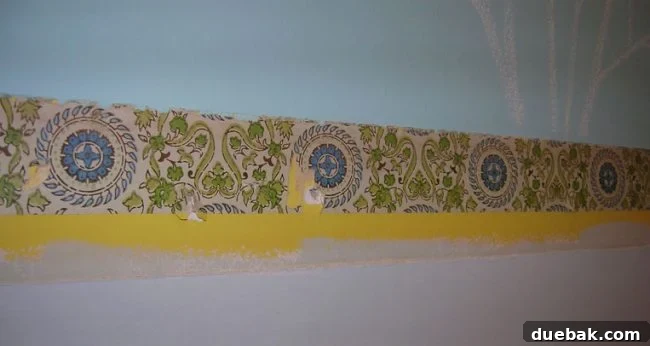 Before and after of chair rail removal, revealing layers of old yellow paint and 1970s wallpaper underneath