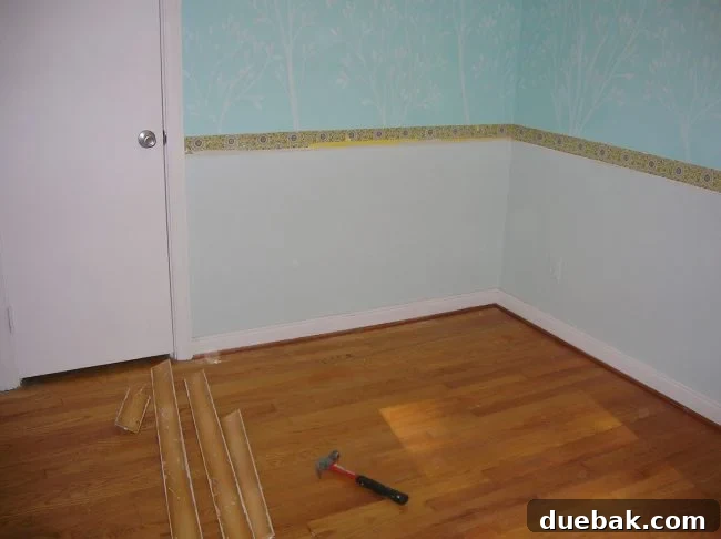 Close-up of the wall where the chair rail was removed, showing exposed vintage paint and wallpaper