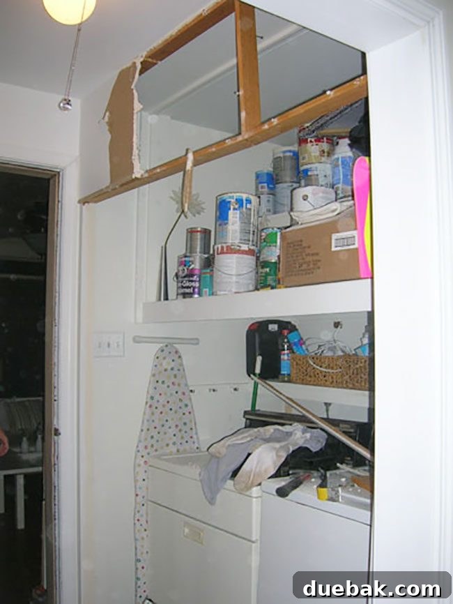 Messy aftermath of drywall demolition in the laundry area, with debris covering the floor and appliances