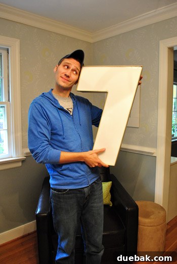 Another playful image of the man with the large number '7', continuing the lighthearted theme of his affection for the new home decor item.