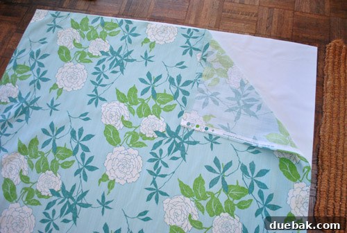Craft Your Own Blackout Curtains 3 Layering an affordable blackout fabric liner behind a colorful floral curtain panel to demonstrate the simple process of creating DIY blackout curtains without sewing.