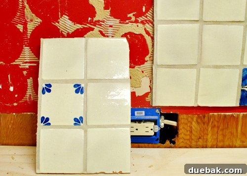 Close-up of old tile backsplash being removed with a screwdriver