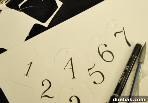 Tracing over sketched numbers on advent calendar tags with a pen.