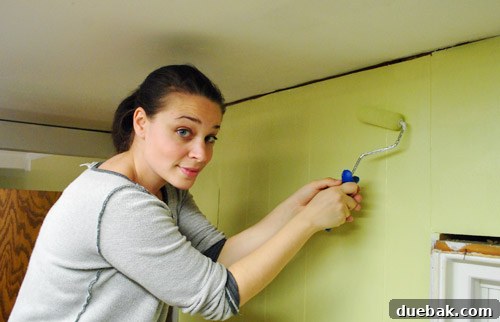 Applying primer to kitchen paneling and ceiling
