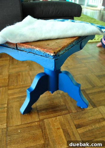 Applying rich navy paint to the primed stool base