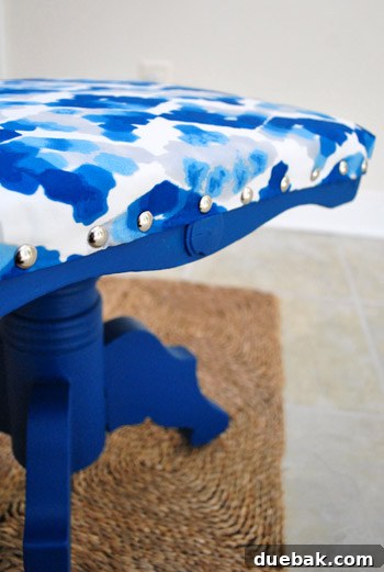 Fully upholstered stool with decorative nail head trim