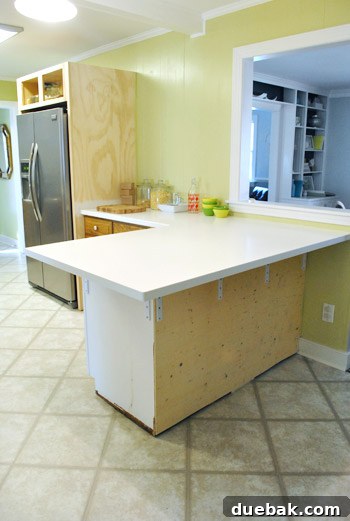 Kitchen peninsula with new Corian countertops, highlighting the curved edges and ample workspace.